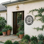 Personalized compass metal wall art displayed on exterior stucco wall with greenery and modern outdoor decor