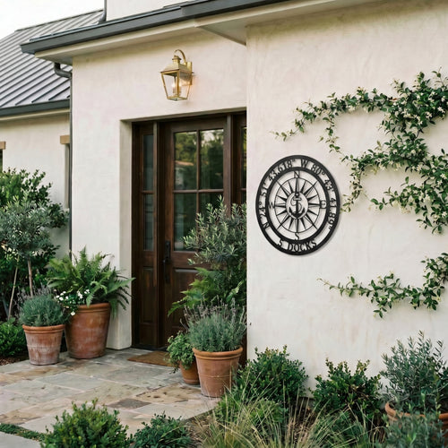 Personalized compass metal wall art displayed on exterior stucco wall with greenery and modern outdoor decor