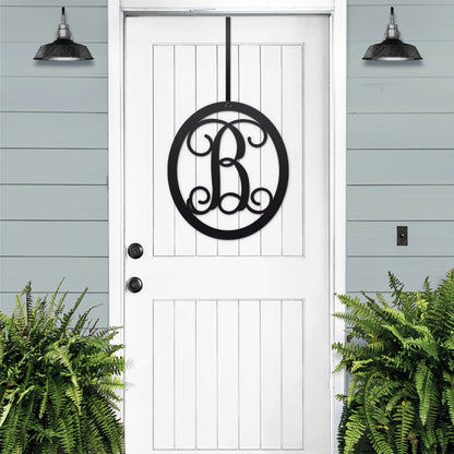 Classy Classic Oval Monogram Door Wreath, featuring a personalized metal monogram on a white door, showcasing elegant craftsmanship for versatile indoor and outdoor use. Ideal for home personalization or gifting.