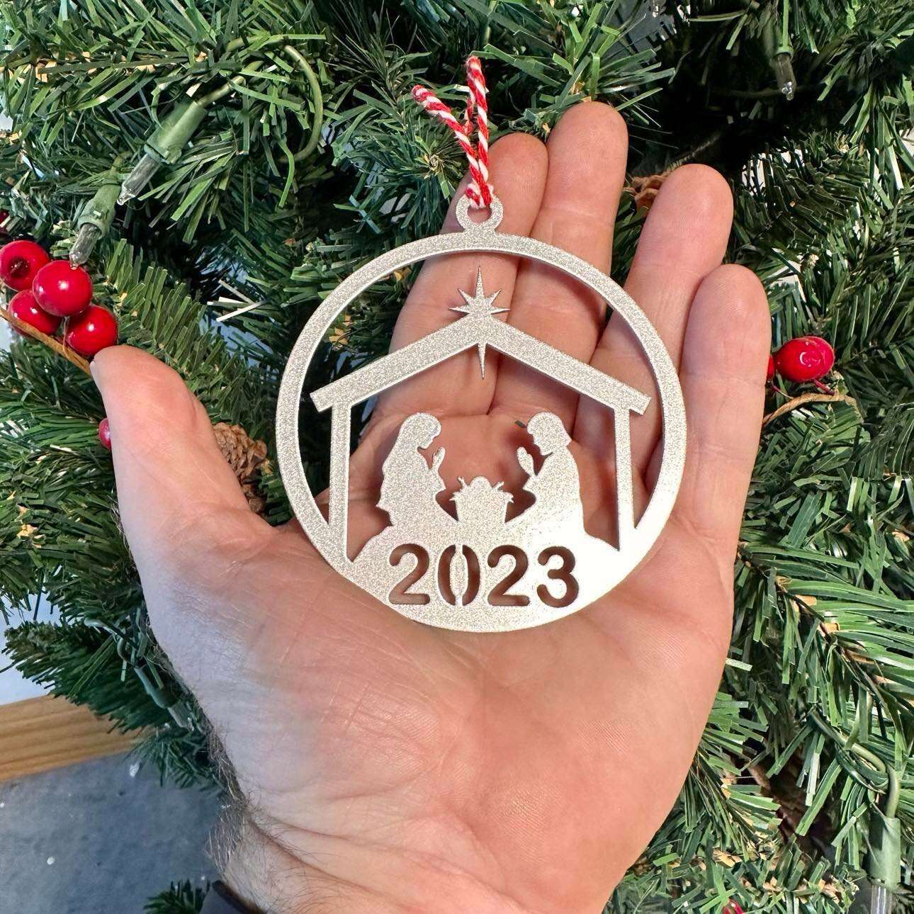 Decorative ornament with 2023 held in hand in front of Christmas tree, festive holiday decoration for seasonal décor and commemorative ornament display