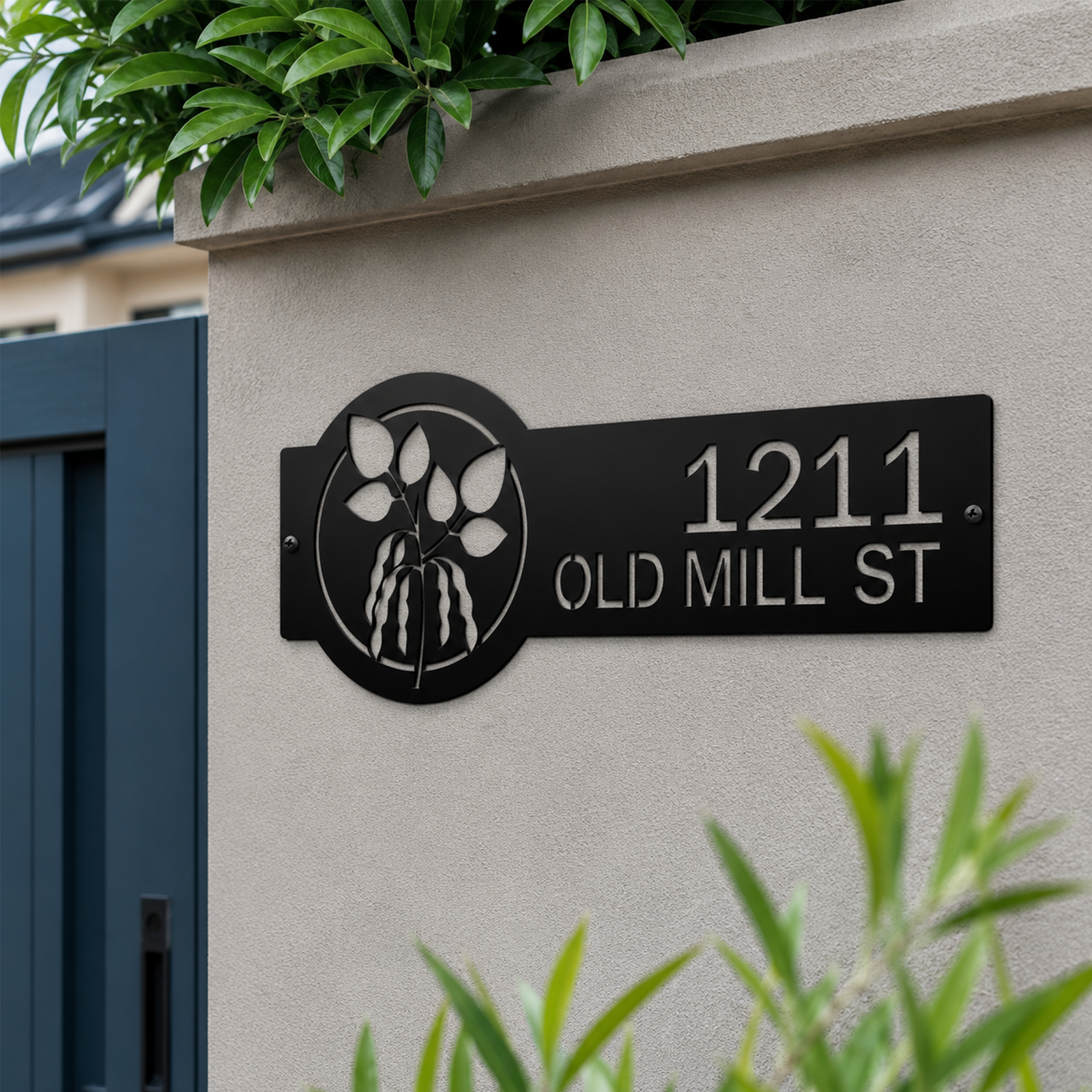 Golden yellow personalized metal address sign with botanical leaf design mounted on modern concrete mailbox pillar displaying 1211 Old Mill St