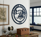 Custom navy blue metal catfish sign mounted on an indoor white wall above a rustic table displaying fishing gear, lures, and a wooden tackle chest.