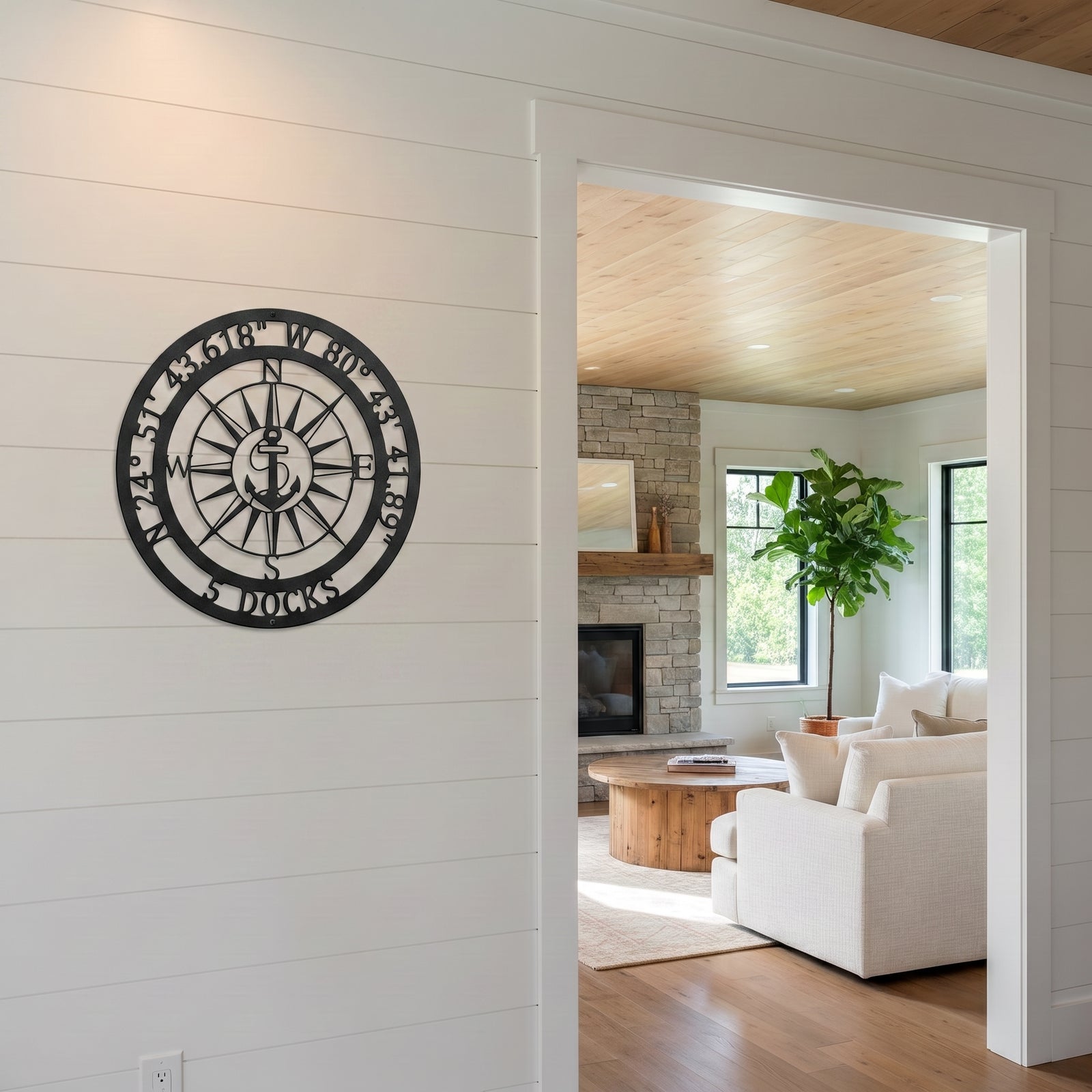 Custom nautical compass metal decor mounted on white shiplap wall beside modern living room entrance