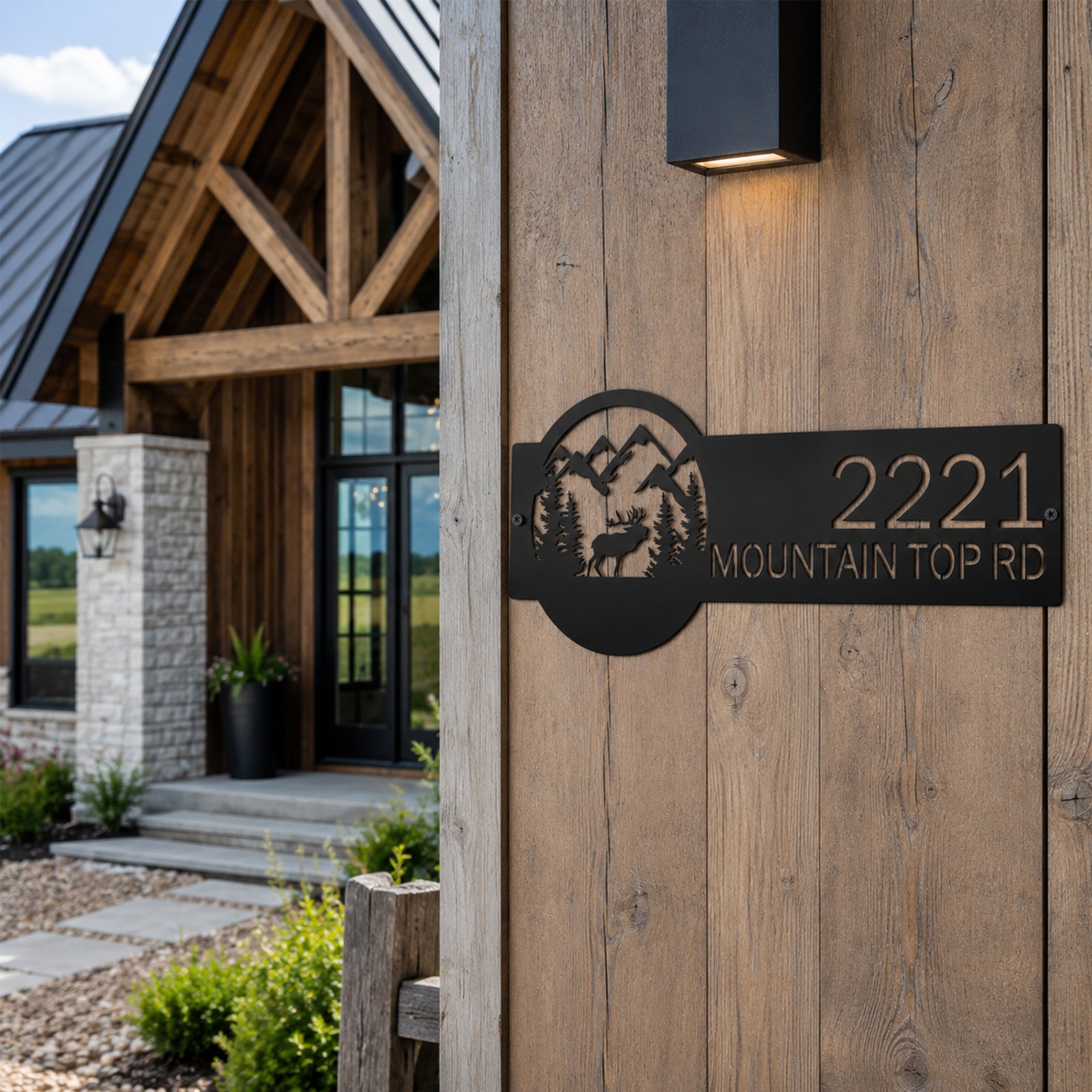 Black elk themed metal address plaque with mountain landscape mounted on wooden exterior post outside cabin home