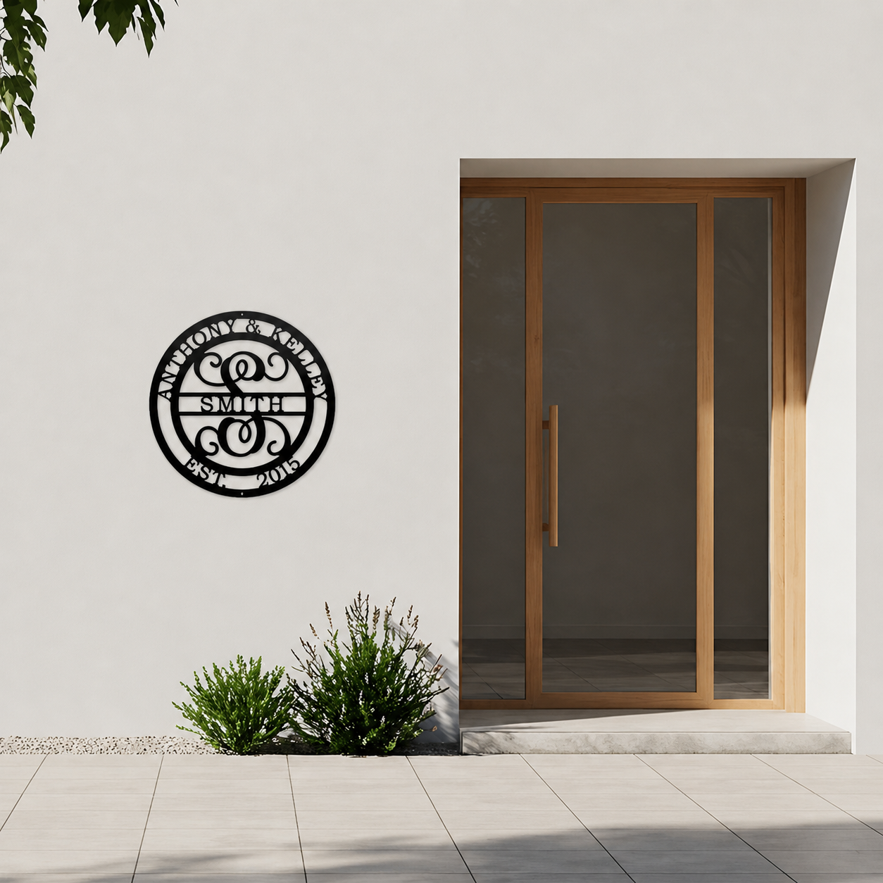 Custom round monogram metal wall sign with family names and established date displayed beside modern front entrance