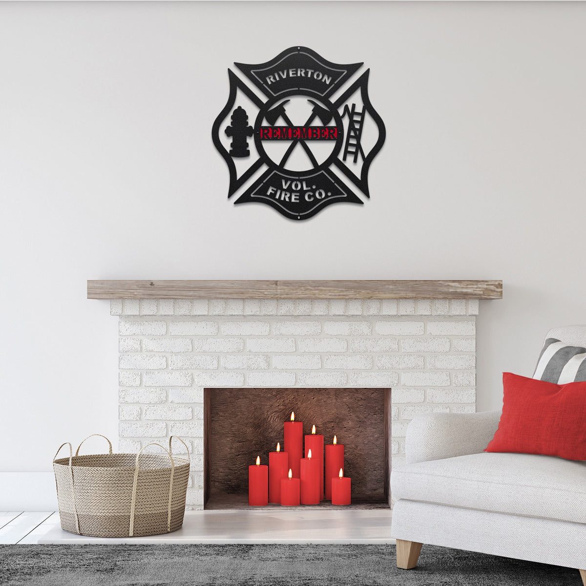 Black decorative wall art of a white wall of a fire department emblem above a fireplace with red candles.