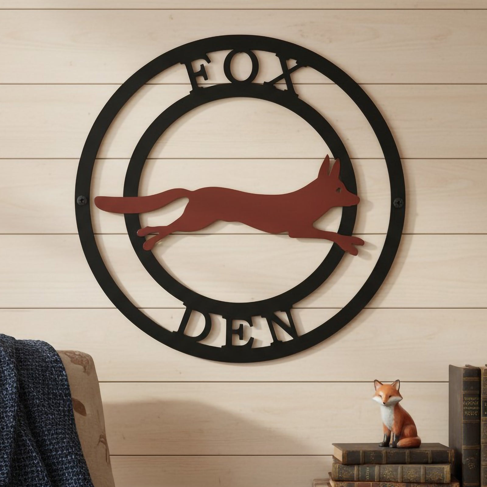 Custom fox den metal wall sign with black circular frame and rust fox design displayed on a cozy wood wall with rustic cabin decor
