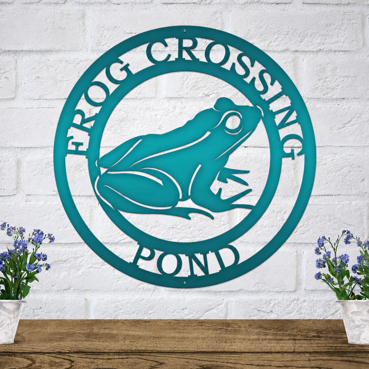 Teal personalized frog crossing pond metal wall sign with frog silhouette mounted on white brick wall outdoor decor display