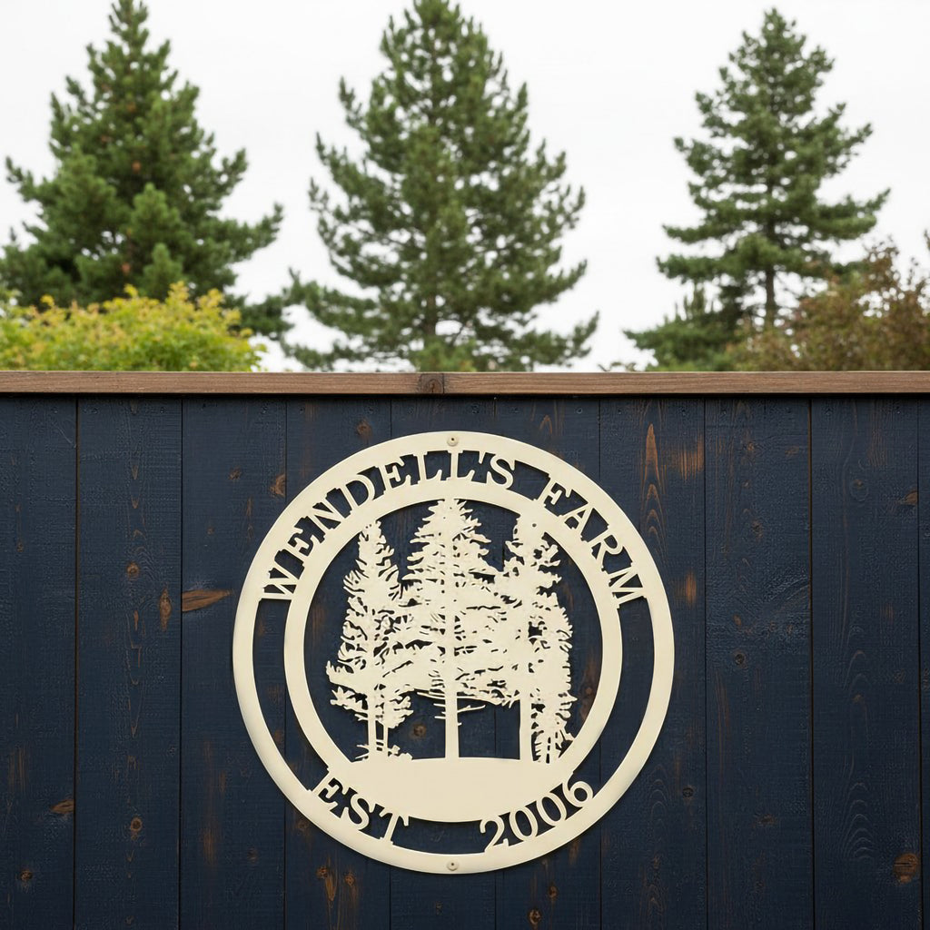 An off-white round metal sign personalized with "Wendell's Farm Est. 2006" featuring a cluster of pine trees, hanging on a dark navy blue wooden privacy fence.