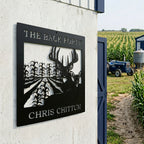 Satin black personalized hunting farm metal sign with deer and cornfield scene displayed near tractor and crop field