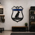 Personalized K9 German Shepherd metal sign displayed on an interior wall with tactical K9 equipment and framed dog artwork, crafted from durable powder-coated metal for indoor or outdoor use.