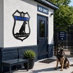 Personalized K9 memorial badge metal sign mounted outside a K9 unit building with a German Shepherd sitting near the entrance
