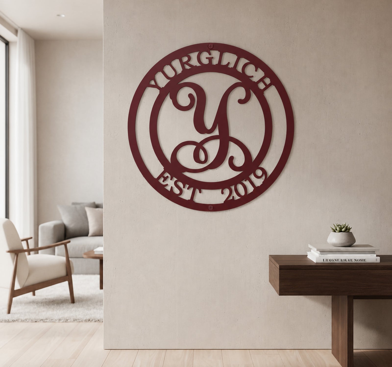 Maroon burgundy custom metal script monogram sign styled on a neutral living room wall above a dark wood entryway table.
