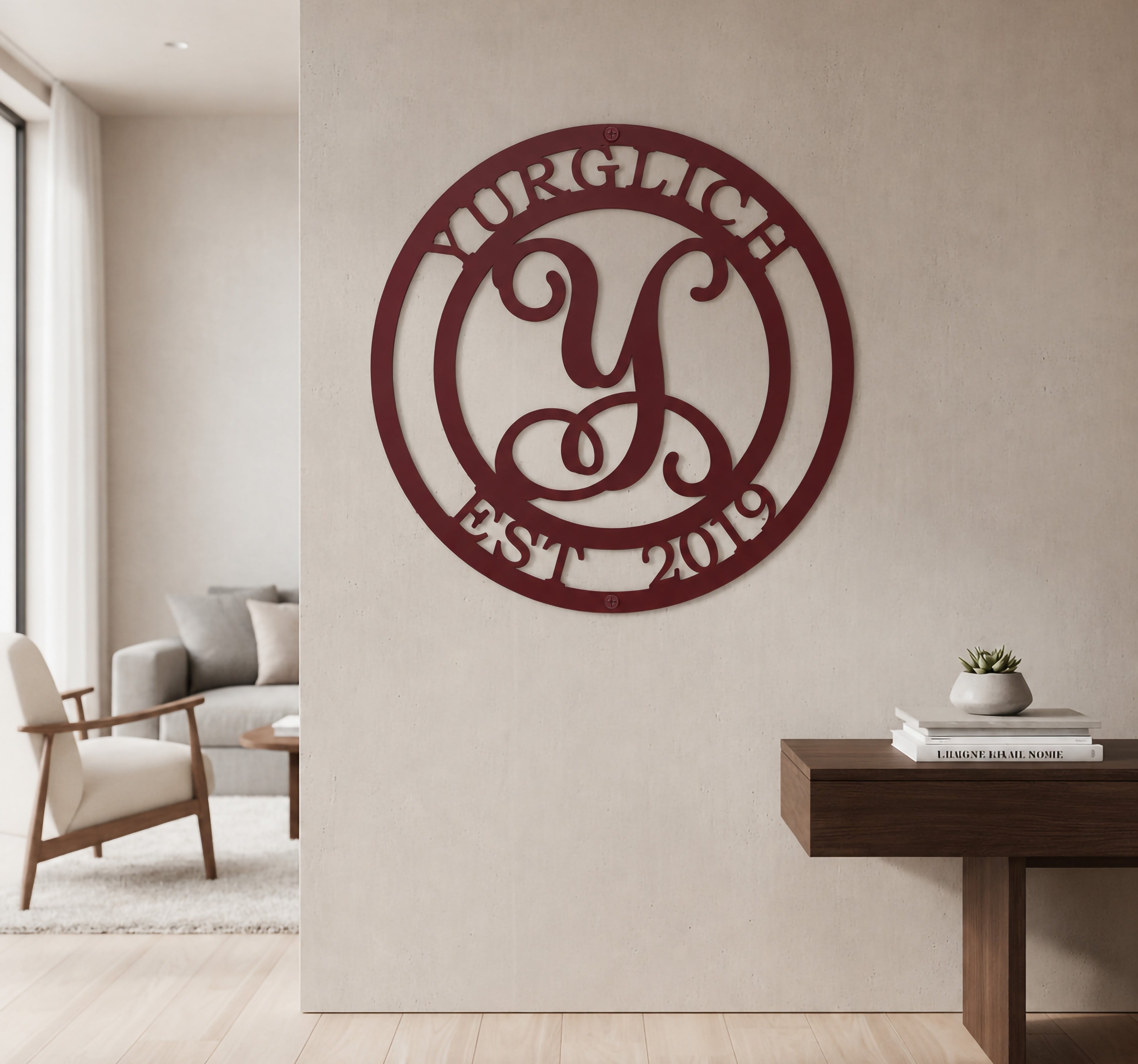Maroon burgundy custom metal script monogram sign styled on a neutral living room wall above a dark wood entryway table.
