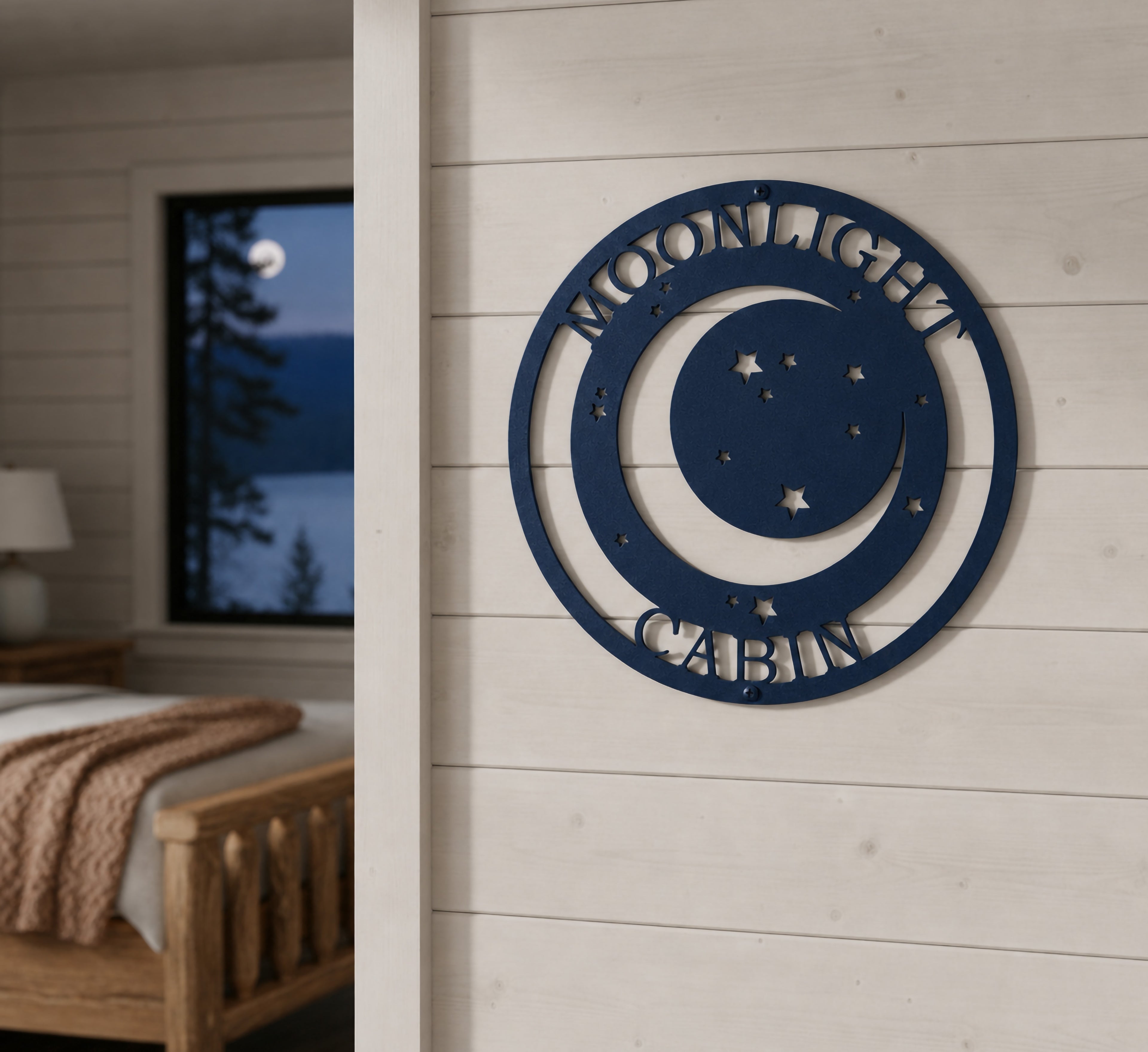 Textured navy blue finish of the custom circular moonlight cabin metal art sign styled on an indoor concrete pillar wall inside a rustic modern bedroom overlooking a misty lake window.