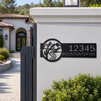 Black personalized mountain road address metal sign on white gate pillar near modern home