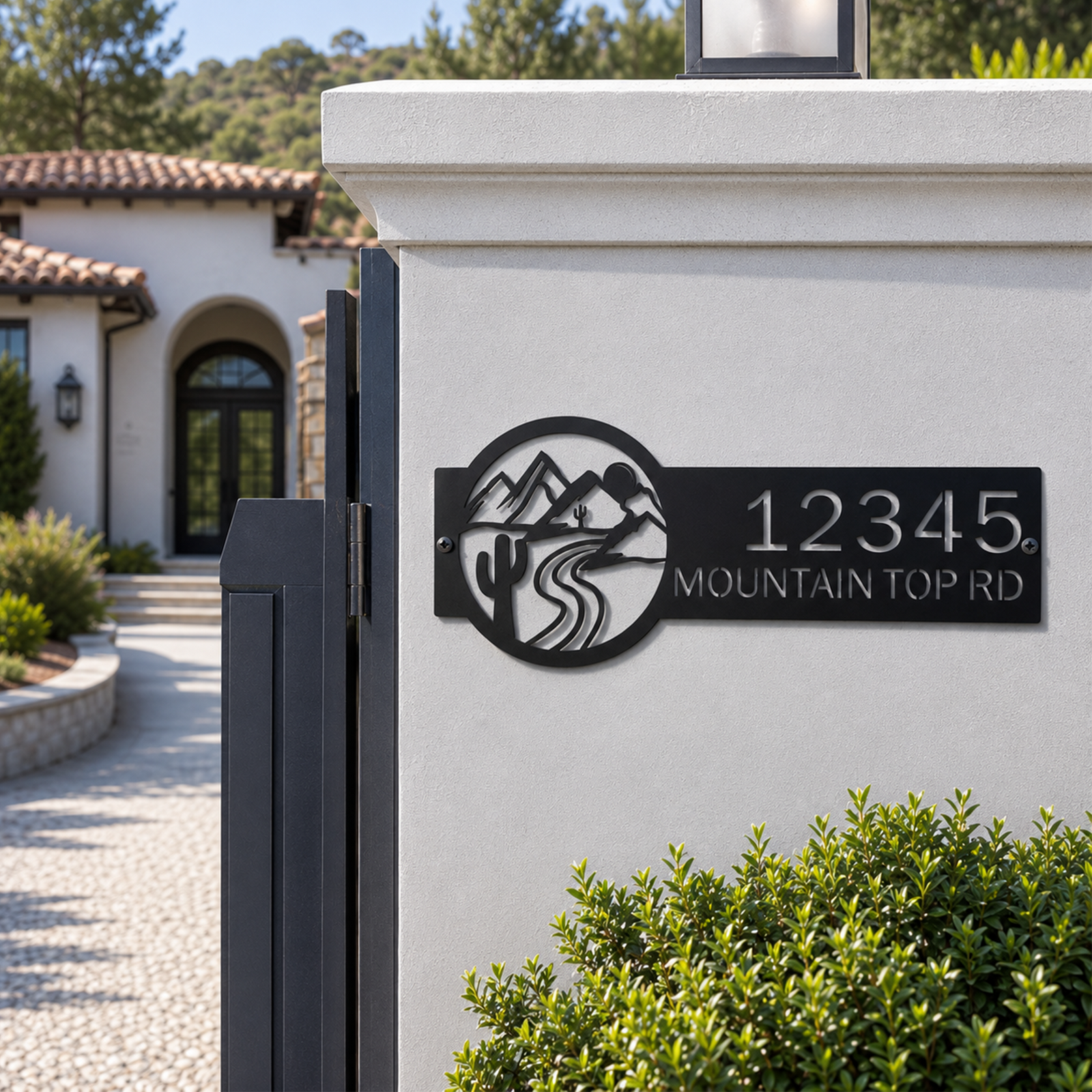 Black personalized mountain road address metal sign on white gate pillar near modern home