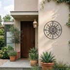 Black compass rose metal wall decor displayed beside modern front entryway with outdoor plants and lantern