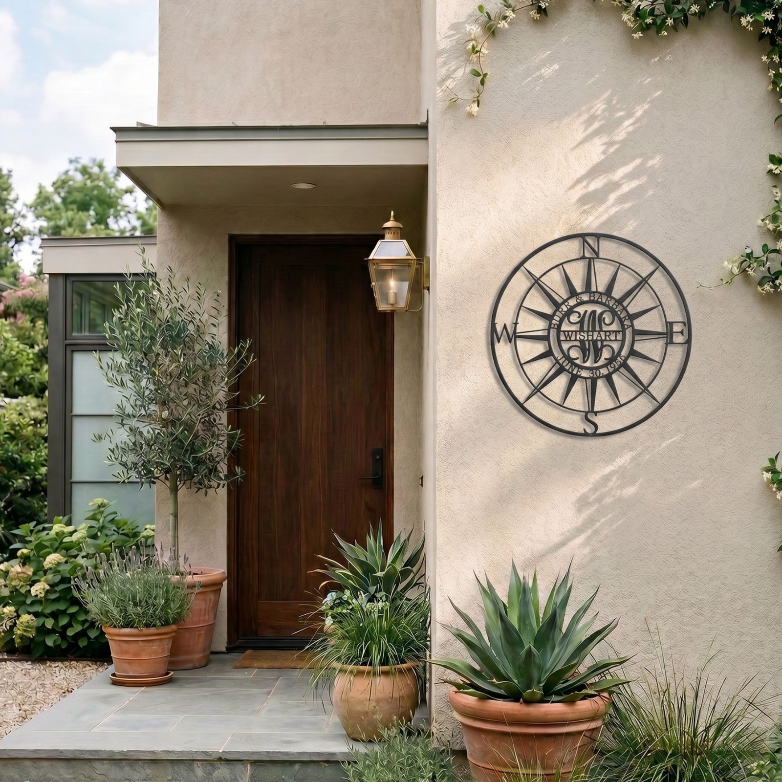 Black compass rose metal wall decor displayed beside modern front entryway with outdoor plants and lantern