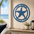 Medium blue finish of a custom metal starfish sign with personalized family text, styled indoors above a wooden entryway console table with beach decor.