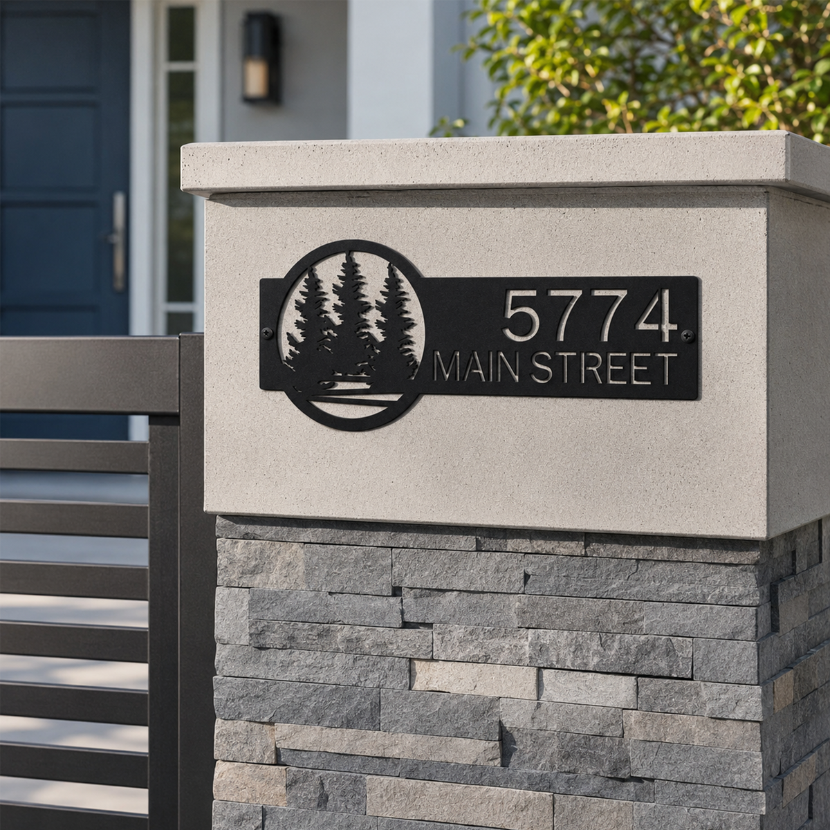 Black custom metal address plaque with pine tree forest design mounted on modern stone mailbox pillar displaying 5774 Main Street