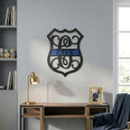 Custom police themed metal monogram wall sign with blue stripe displayed above wooden console table in office setting