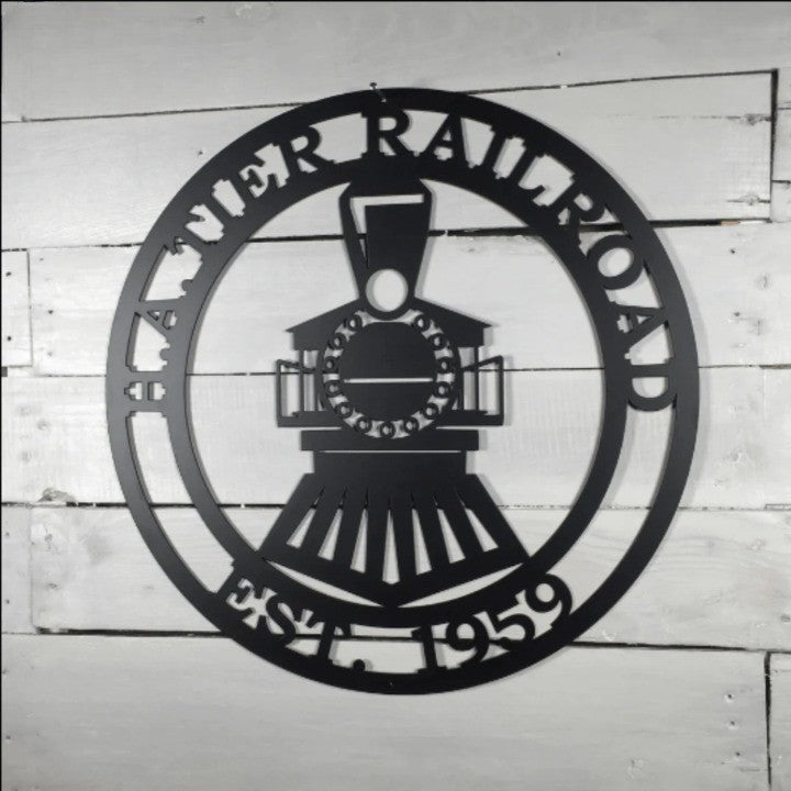 Black metal steam engine train sign with custom name and date on a white rustic wooden shiplap wall background.