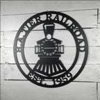 Black metal steam engine train sign with custom name and date on a white rustic wooden shiplap wall background.