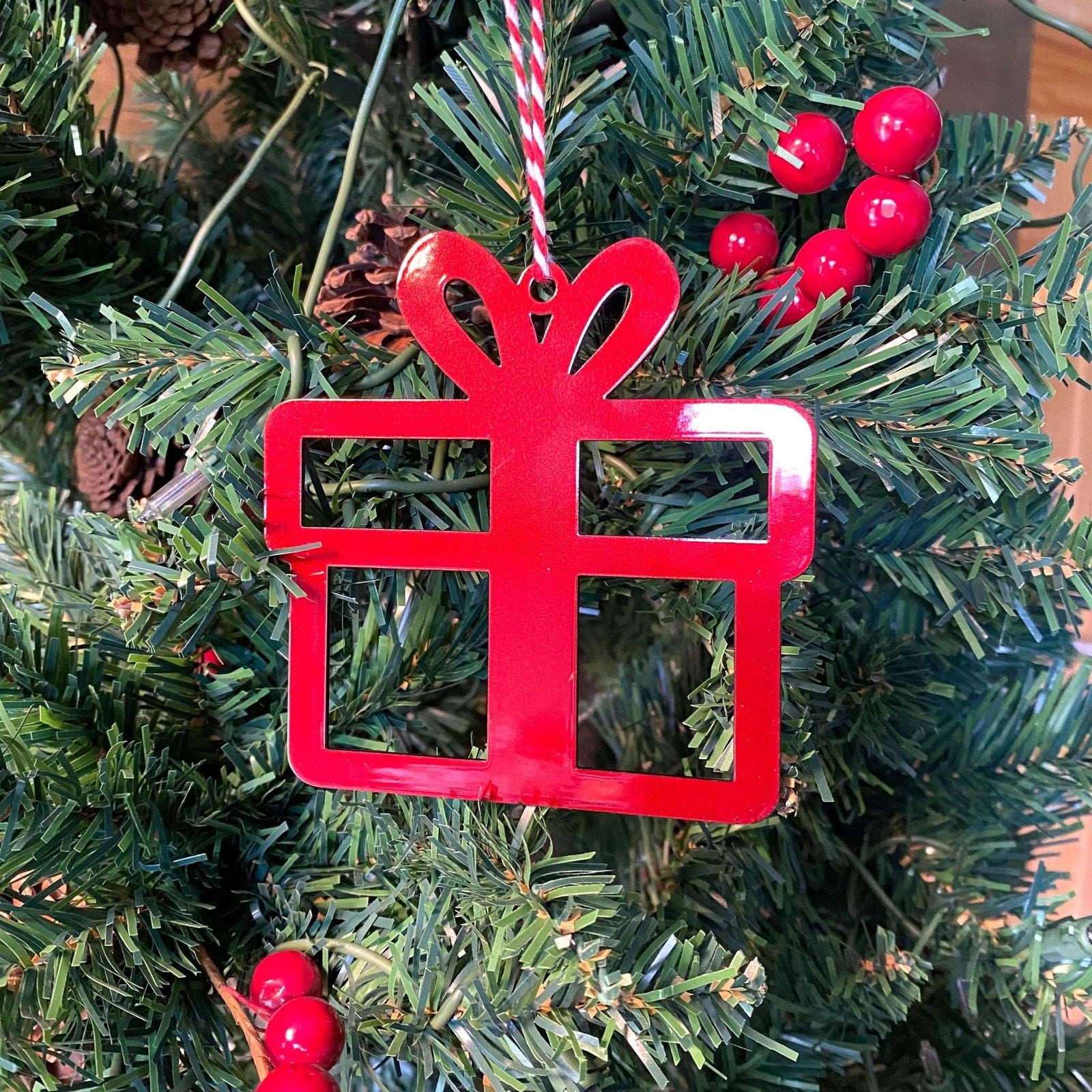Red metal Christmas ball ornament hanging on festive Christmas tree branches with holiday decor