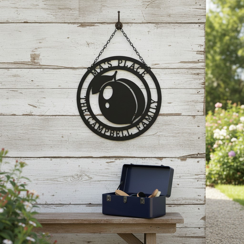 Matte black customized round hanging metal peach sign displayed on a weathered white barn wood wall above a wooden bench holding an open blue tool box.