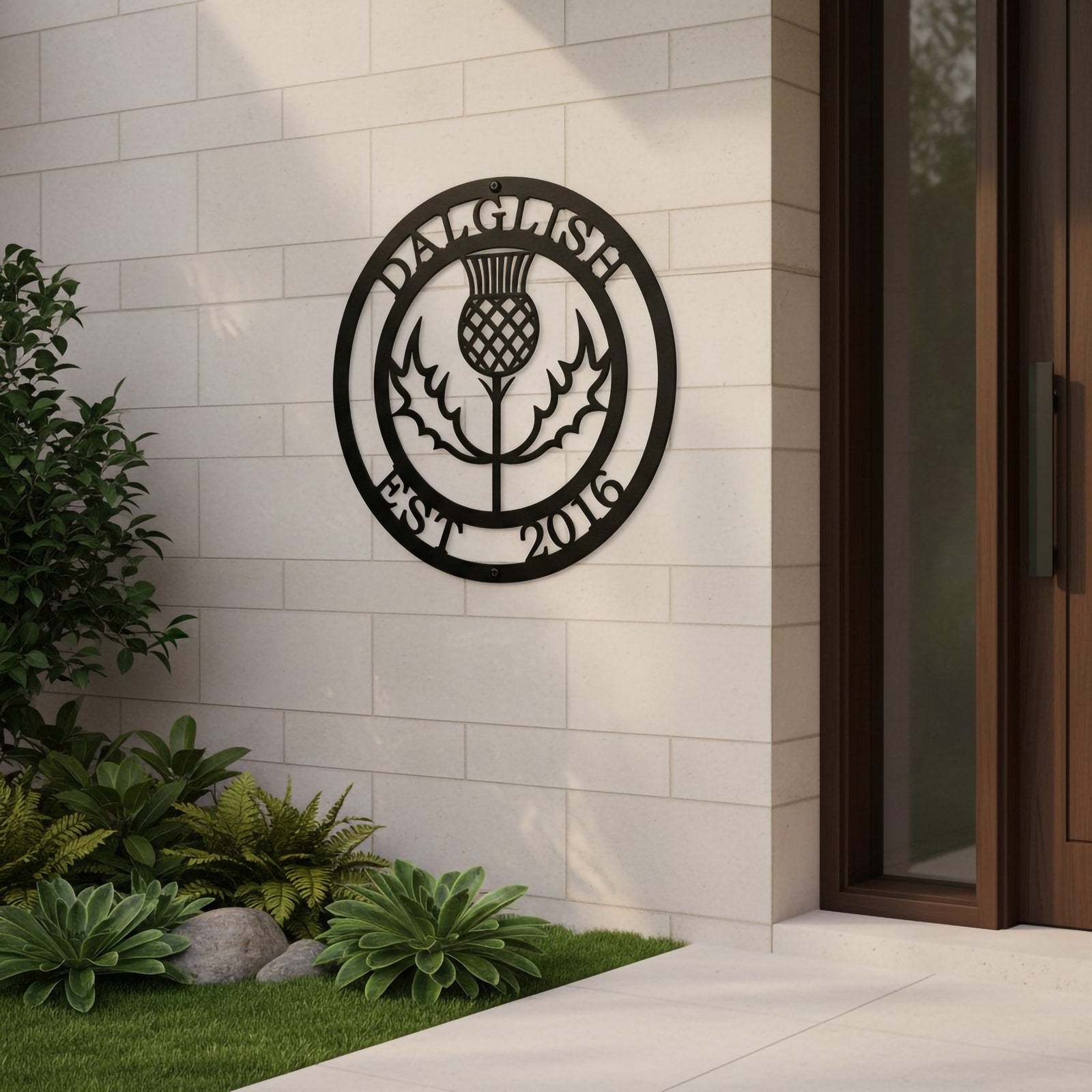 Satin black custom round metal sign featuring a laser-cut Scottish thistle and personalized family name mounted on a modern light gray tiled outdoor wall.