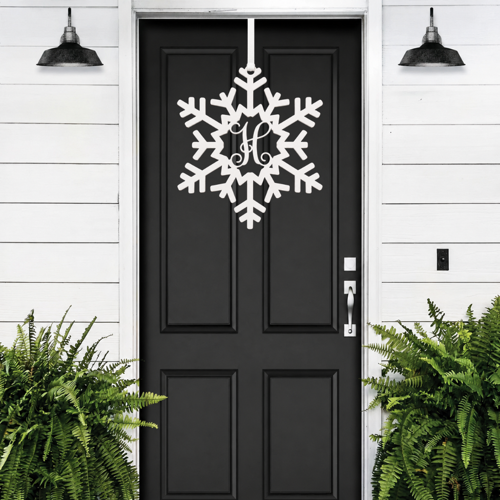 Personalized snowflake monogram door hanger in white displayed on black front door for winter porch decor and holiday entryway style