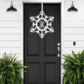 Personalized snowflake monogram door hanger in white displayed on black front door for winter porch decor and holiday entryway style