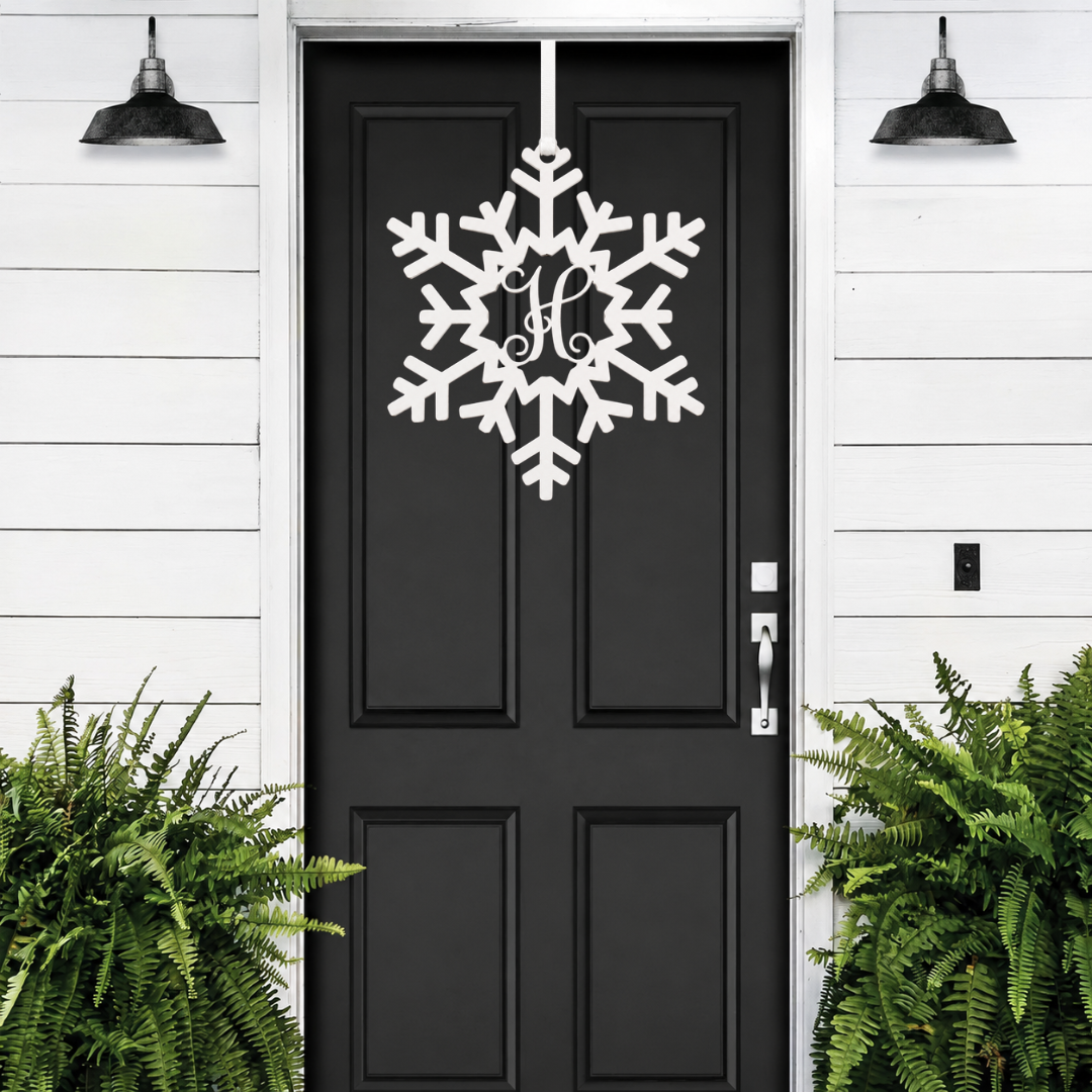 Personalized snowflake monogram door hanger in white displayed on black front door for winter porch decor and holiday entryway style