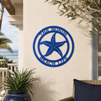 Vibrant blue custom metal starfish family sign mounted on an outdoor stucco wall above a large glossy blue planter on a sunny patio.