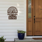 Custom Espresso metal address sign featuring a tree design, family name Hundley, and house number 8705 mounted on white exterior siding near a front door.