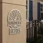 Custom Satin Silver metal address sign featuring a tree design, family name Hundley, and house number 8705 mounted on a stucco entry pillar.