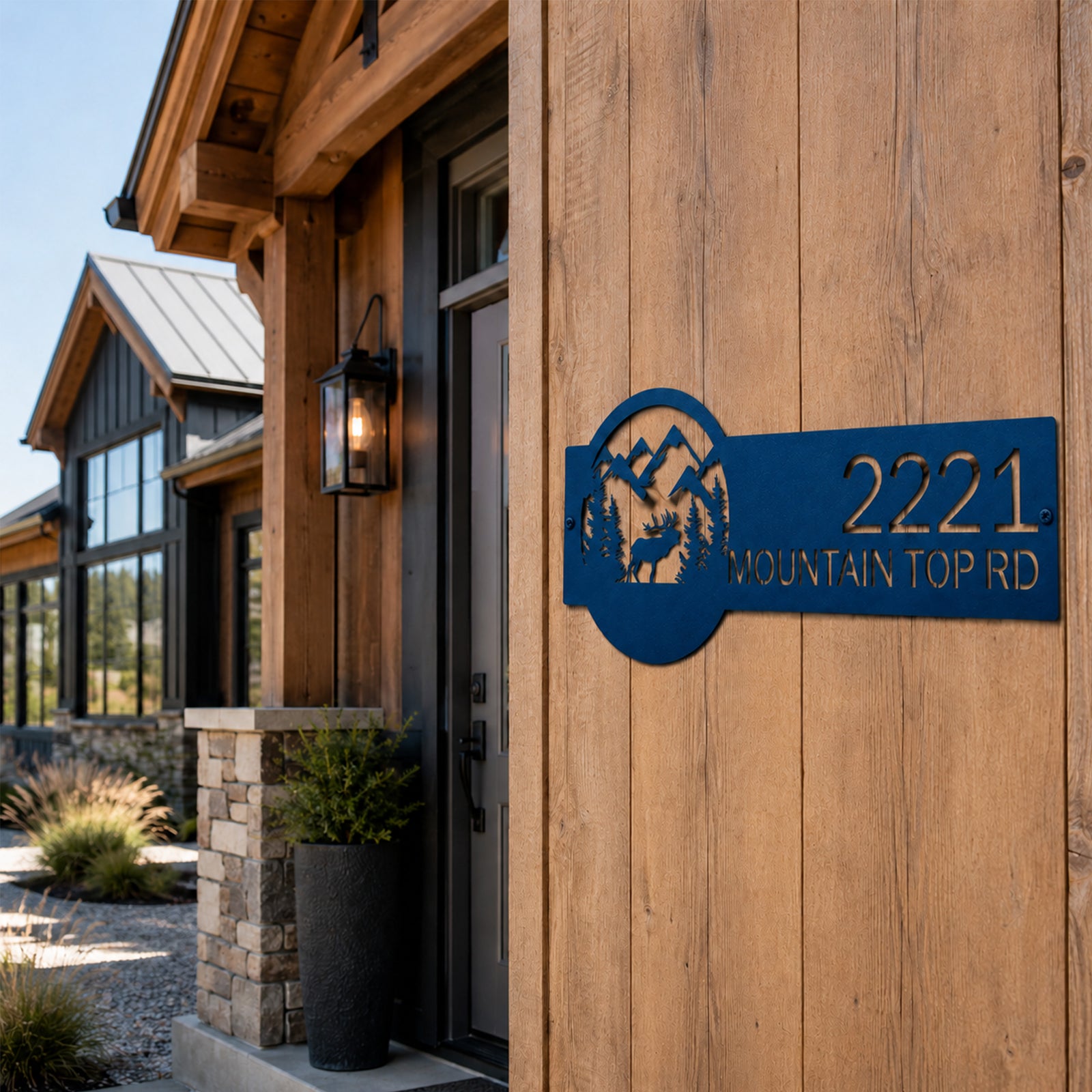 Blue custom wilderness address plaque with elk silhouette and mountain scene mounted on wooden farmhouse exterior