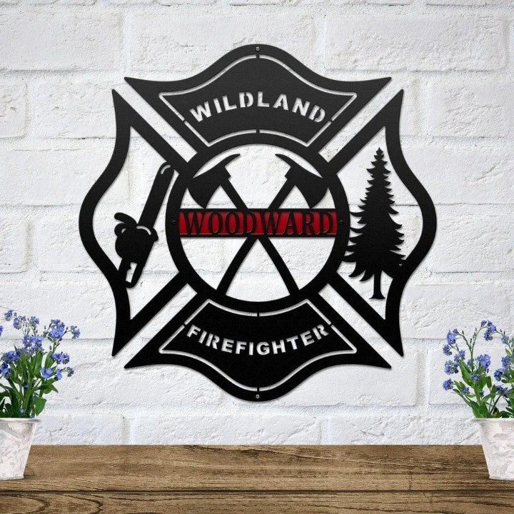 Black metal Maltese cross sign with axes, chainsaw, and tree, featuring a personalized red Woodward nameplate.