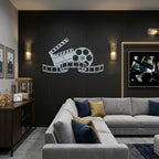 Polished chrome movie reel and clapperboard metal wall art displayed in a modern home theater room