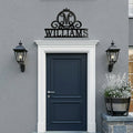 Black Williams monogram metal family sign displayed above a modern exterior front door with black lantern wall lights and gray stucco wall