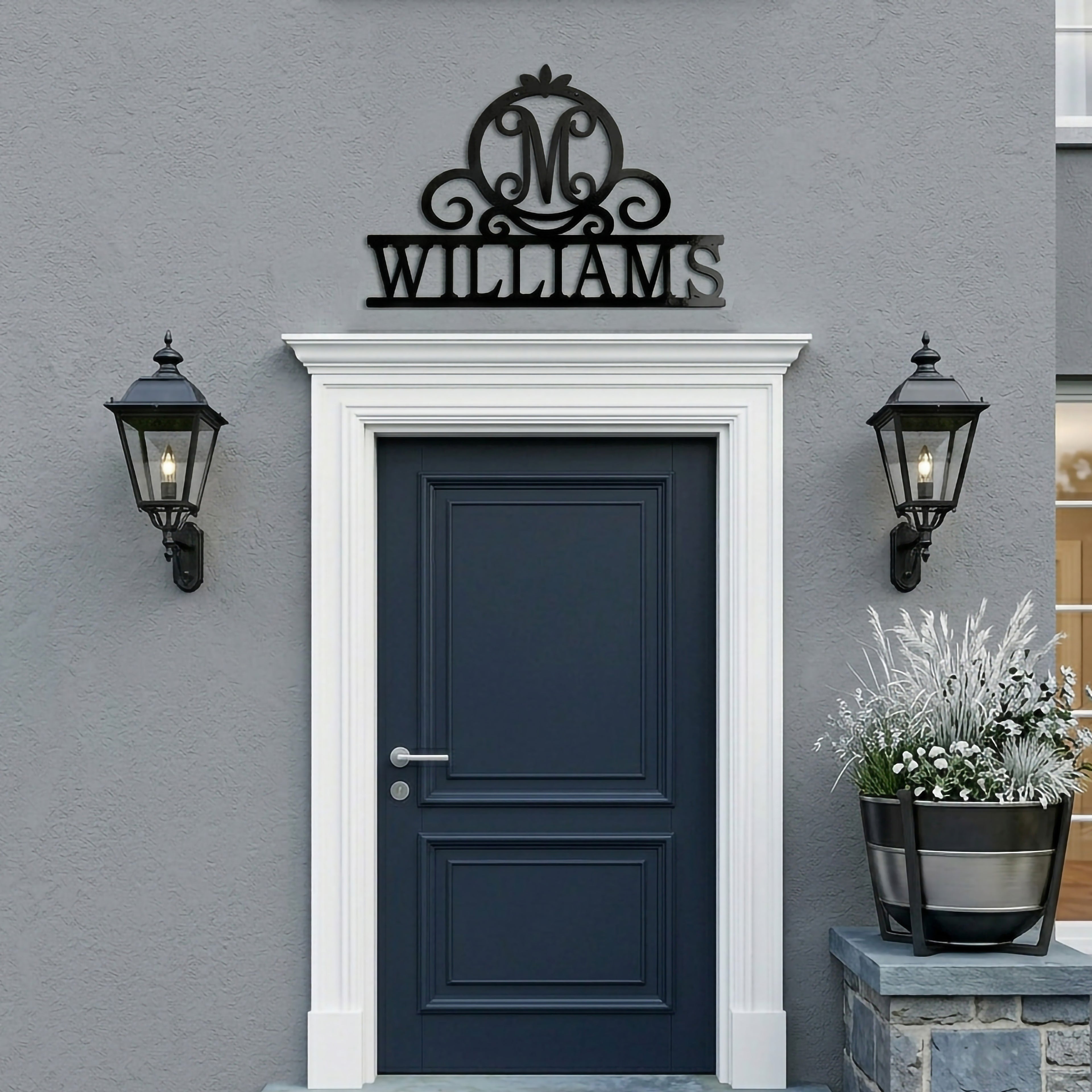 Black Williams monogram metal family sign displayed above a modern exterior front door with black lantern wall lights and gray stucco wall