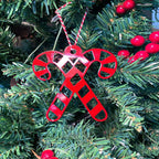 Red candy cane ornament hanging on Christmas tree with green leaves and red berries, festive holiday decoration for seasonal décor and Christmas tree display