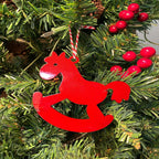 Red rocking horse ornament hanging on Christmas tree with red berries, festive holiday decoration for seasonal décor and Christmas tree display