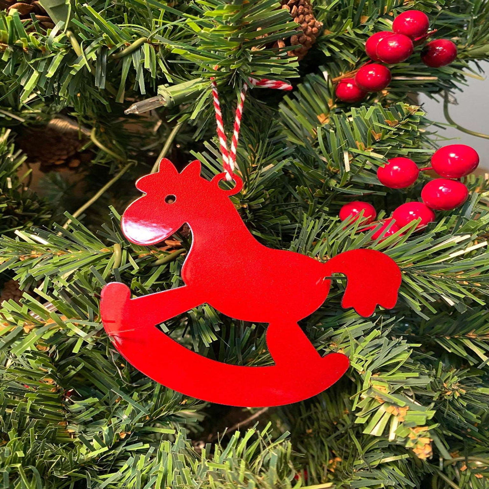 Red rocking horse ornament hanging on Christmas tree with red berries, festive holiday decoration for seasonal décor and Christmas tree display