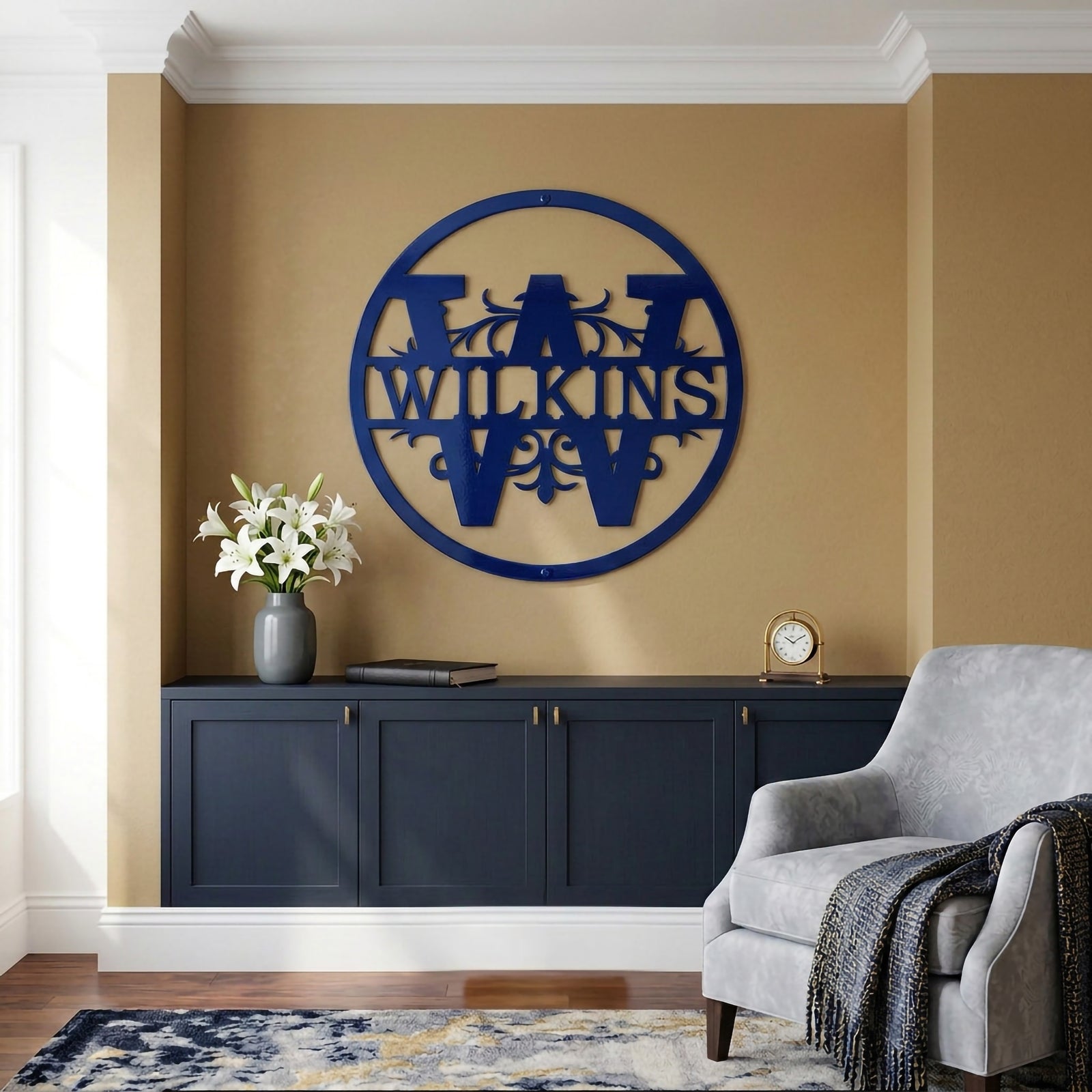 Deep royal blue finish of the custom circular split monogram family sign with text Wilkins, styled on a warm gold accent wall above a dark navy blue built-in console cabinet next to a grey armchair.