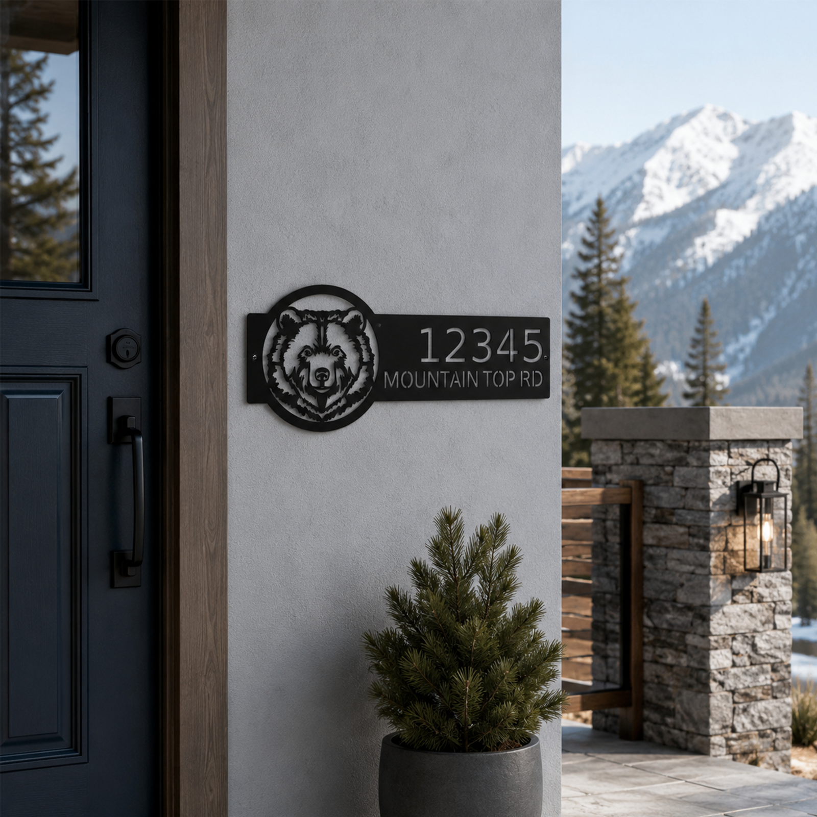Black custom bear address plaque displayed beside modern mountain cabin entry with snowy mountain background