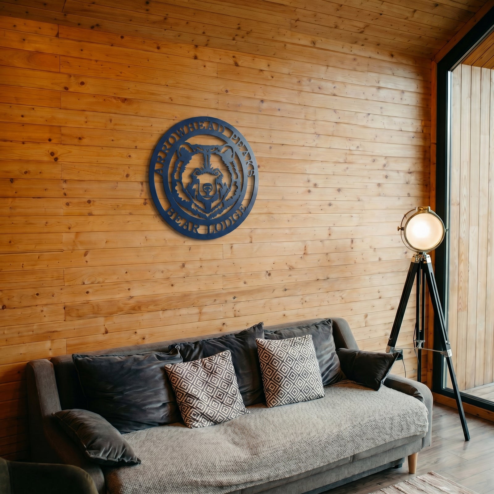 Arrowhead Peaks Bear Lodge metal wall art displayed above sofa in rustic cabin style living room with wood plank walls