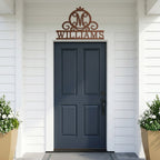 Textured copper Williams monogram metal sign displayed above a dark blue front door on white siding porch entrance