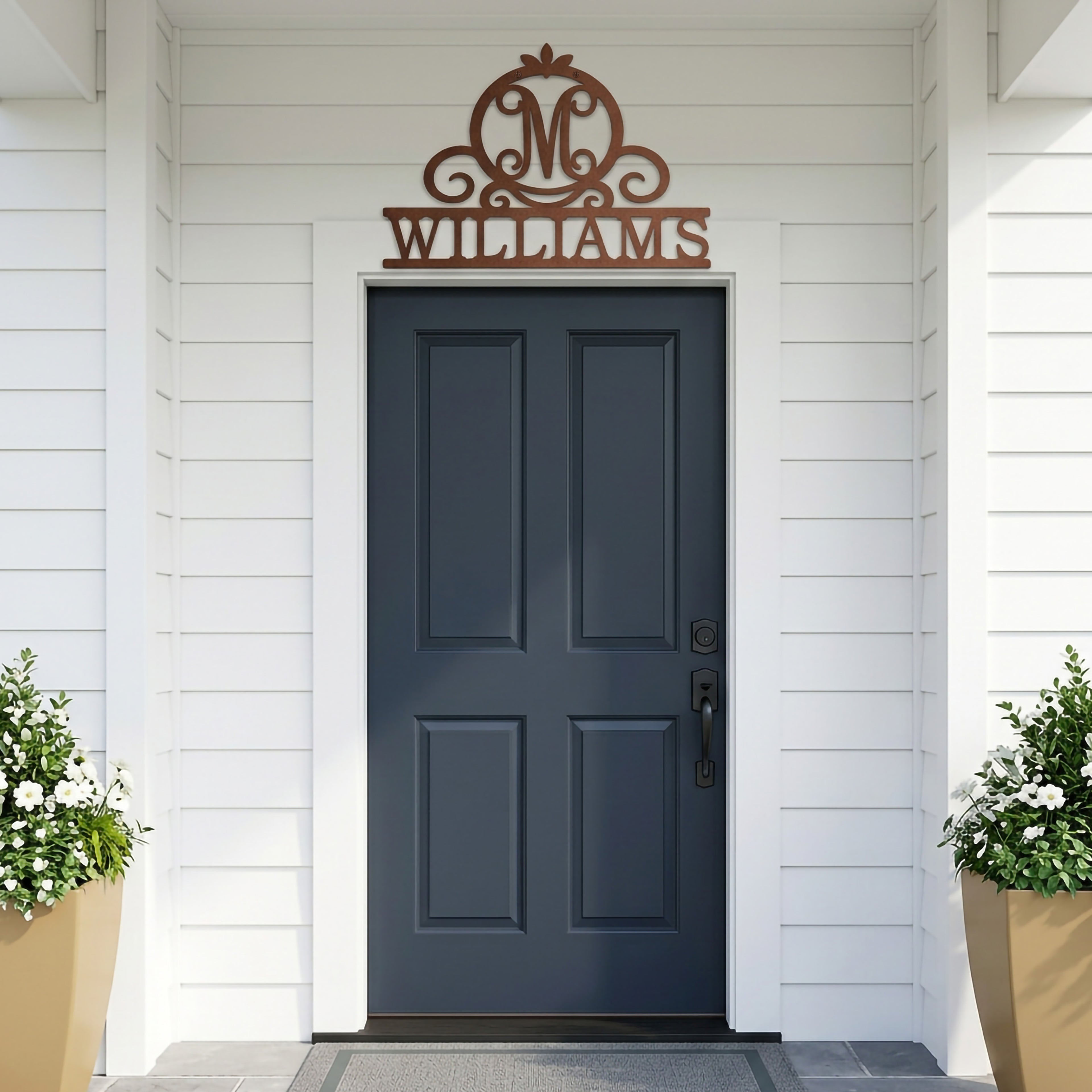 Textured copper Williams monogram metal sign displayed above a dark blue front door on white siding porch entrance